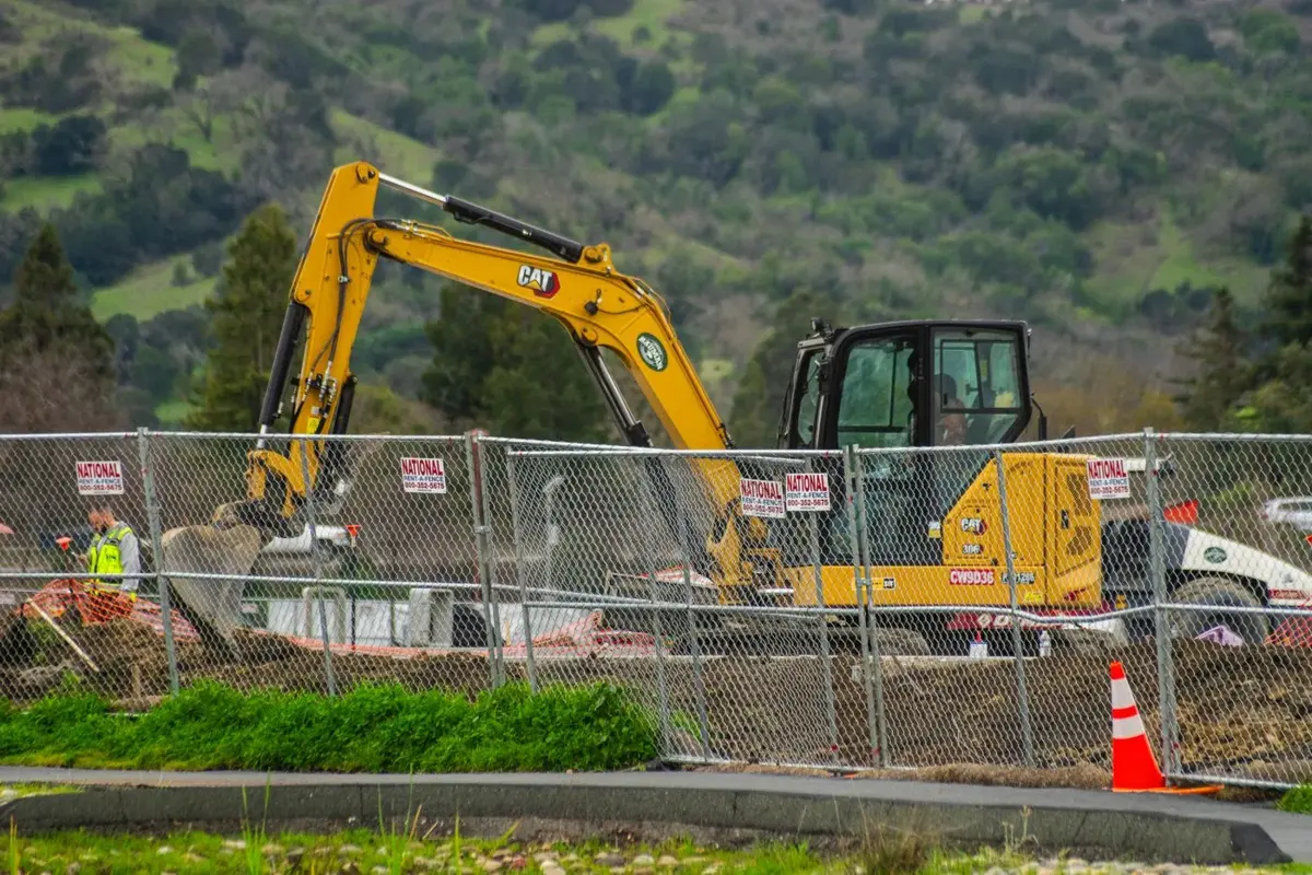 Excavator working behind site safety fencing